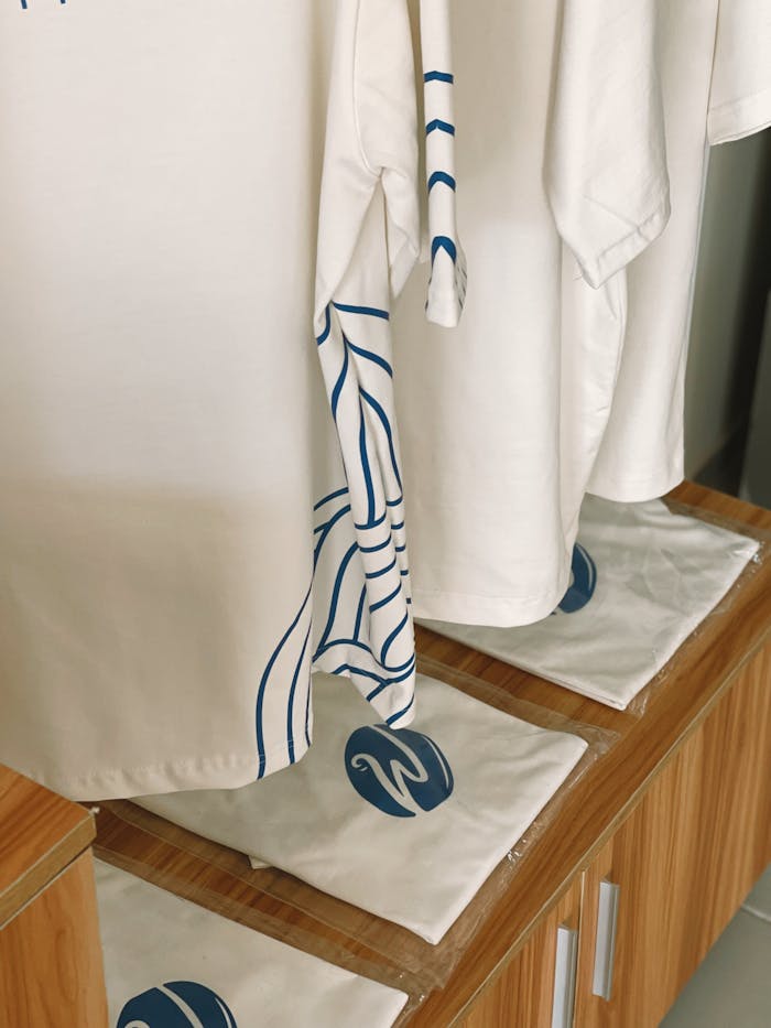 White shirts with blue accents on display, showcasing minimalistic design and clean presentation.